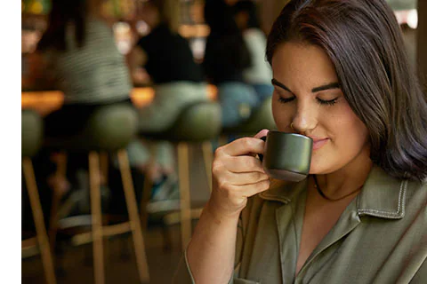 Woman smells the aromas in an espresso cup.