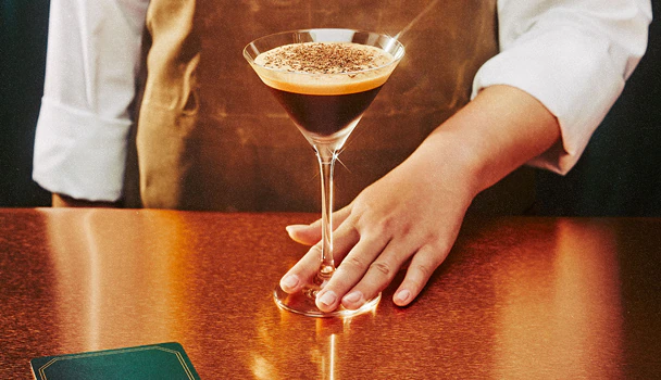 A bartender serves an espresso martini.