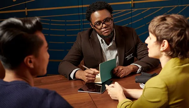 A event specialist listens to two people and writes notes.