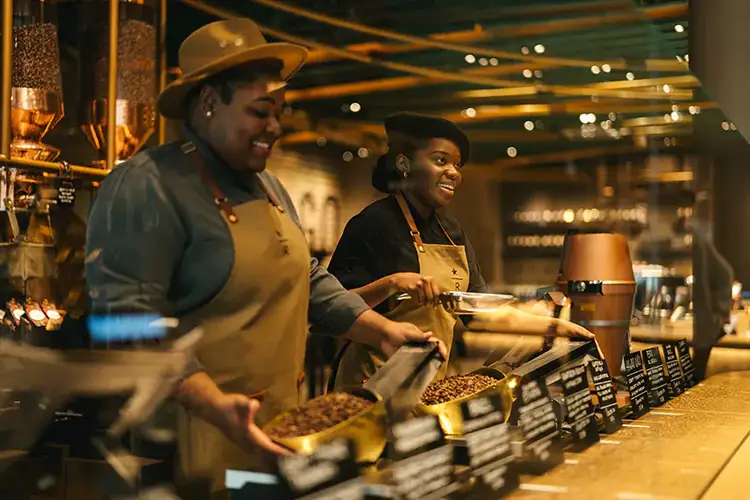 Two smiling baristas behind the counter of the Scooping Bar in the Chicago Roastery