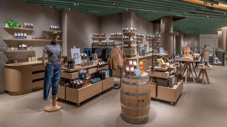 Display tables with a variety of products, including coffee, drinkware, brewing equipment and apparel, plus a mannequin and whiskey barrel in the foreground