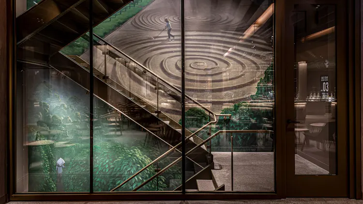 Part of a multi-floor wall mural in the Chicago Roastery stairwell, showing coffee plant greenery and a person raking drying coffee beans outdoors into a large spiral shape