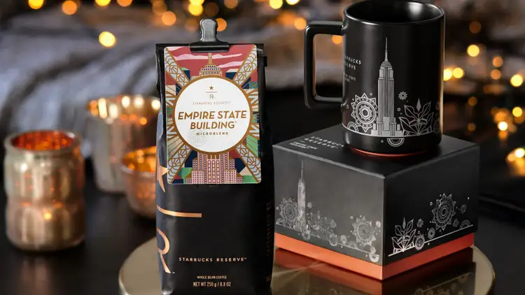 A bag of Starbucks Reserve® Empire State Building® coffee sits next to a mug with the New York City skyline.