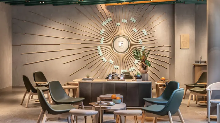 A large, geometric wall sculpture with a central circular shape with multiple spokes that are flush to the wall, and with words on the spokes that describe tasting components of coffee including "CITRUS", "SPICY" and "CHOCOLATE"