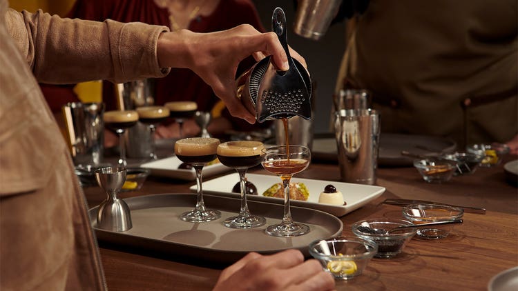 A bartender using a strainer to pour a martini.