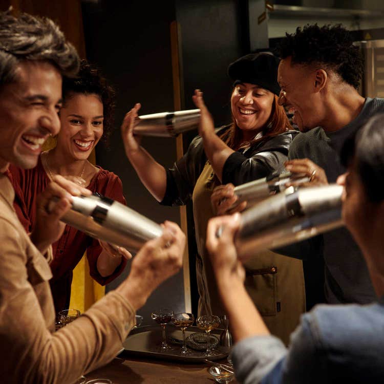 A group of people using metal cocktail shakers.